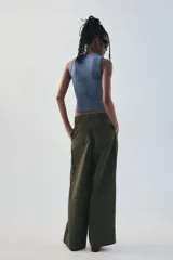 Pantalón verde militar de tiro medio, con bolsillos delanteros, pliegues y tejido con efecto lavado. Cuenta con cierre frontal con cremallera y gancho metálico.