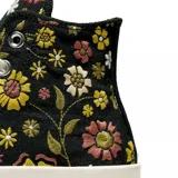 Championes Converse modelo Chuck 70 de caña alta, con diseño estampado de flores en tonos amarillos, rosas y verdes sobre base negra. Presenta el parche clásico de la marca en el lateral, puntera de goma y suela de plataforma en color crema.