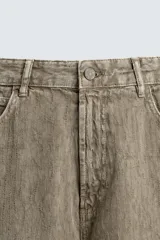 Pantalón de corte baggy fit confeccionado en tejido de algodón con textura y efecto lavado. Presenta diseño de cinco bolsillos, cierre frontal con cremallera y botón.