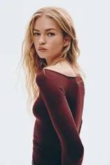 Remera de manga larga color bordó oscuro, con escote asimétrico de un solo hombro y frunces laterales que generan un efecto drapeado.