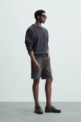 Bermuda de denim de algodón con elasticidad, color negro lavado. Modelo de tiro medio con corte regular fit, cinco bolsillos y cierre frontal con cremallera y botón.