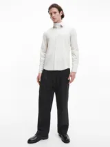 Camisa de manga larga color blanco hueso, de corte slim, con cuello tradicional y cierre frontal de botones.