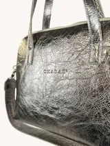 Cartera tipo bowling de cuero genuino color peltre con textura craquelada. Tiene doble asa corta de cuero y correa larga de cinta con logo de la marca.