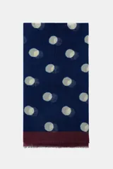 Pañuelo rectangular de gran tamaño con estampado de lunares claros sobre fondo azul marino y borde inferior en color bordó con terminaciones deshilachadas.