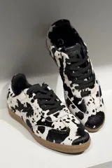Championes de cuero vacuno con acabado brillante tipo charol, color azul marino, con cordones al tono y suela de goma color caramelo.