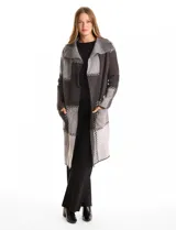 Cardigan largo tejido con diseño patchwork en tonos grises y negros. Presenta cuello con amplia solapa, diseño abierto sin botones y bolsillos delanteros amplios.