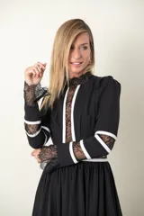 Vestido midi blanco con detalles de encaje y vivos negros. Tiene cuello mao, mangas largas con puños de encaje y falda amplia con tul de armar.