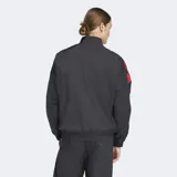 Campera deportiva Adidas de corte holgado, con cierre frontal de cremallera y cuello alto. Presenta un diseño en bloques de color negro con detalles en rojo en las mangas, confeccionada en tejido técnico reciclado.