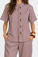 Blusa a rayas de manga corta, con cuello mao y cierre frontal con alamares y botones. Confeccionada en algodón.