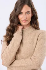 Campera tejida de abrigo color beige, con cierre frontal, cuello alto y bolsillos laterales.