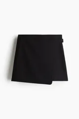 Short pollera negro de tiro alto con diseño cruzado tipo pareo en el frente, asegurado con un cinturón cosido y hebilla revestida. Presenta cierre oculto y cierre de corchete en un lateral.