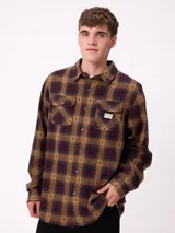 Camisa de manga larga confeccionada en franela de algodón, con diseño de cuadros en tonos verde y marrón. Presenta cuello clásico, cierre frontal con botones y dos bolsillos en el pecho con solapa.