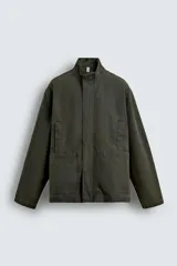 Parka de algodón con acabado lavado, color verde oscuro, de corte relajado. Presenta cuello subido, cierre frontal oculto por solapa con botones a presión, bolsillos de vivo en el pecho y bolsillos plastrón en la cadera.