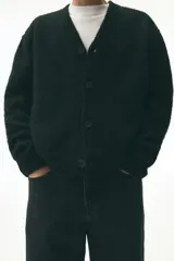 Cárdigan negro de punto peludo suave, con cuello en V pronunciado y cierre frontal de botones. Presenta remates acanalados en puños y bajo.