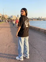 Remera negra de algodón con corte oversize y estampado en la espalda de una paloma blanca y la inscripción "Vinnare - The Brand of the Moment".
