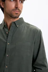 Camisa de manga larga confeccionada en micropana color verde militar, con cuello abotonado, bolsillo frontal y cierre de botones.
