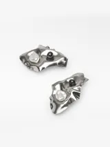 Pendientes metálicos con diseño en relieve de forma orgánica, decorados con una perla natural y una cuenta oscura. Poseen cierre de broche.