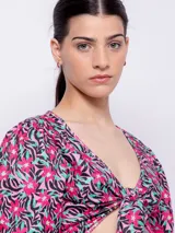Top estampado con flores rosas, hojas verdes y líneas negras, de manga corta abullonada con nudo en el escote.