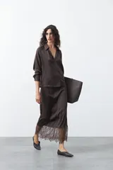 Falda midi de caída fluida color marrón oscuro, con cintura elastizada y detalle de encaje en el bajo.