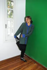 Saco tejido a máquina con rayas verticales negras y marrones, cuello camisero y botones rojos.