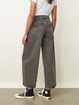 Jean de corte wide leg en color gris con efecto lavado. Presenta tiro medio, cierre frontal con botón y bolsillos laterales y traseros.