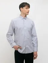 Camisa de manga larga de tejido Oxford color celeste, con cuello button-down, cierre frontal de botones y un bolsillo aplicado en el pecho.