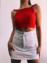 Crop top negro con textura brillante, breteles anchos con volados y espalda descubierta que se ata con lazos.