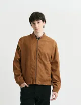 Campera tipo bomber de color marrón, confeccionada en tejido con textura similar a la gamuza, con cierre frontal completo, cuello redondo y puños elásticos.