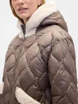 Campera acolchada color beige con diseño de costuras onduladas, cierre frontal, capucha y bolsillos frontales con detalles en corderito blanco.