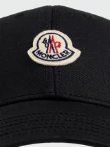 Gorra de baseball Moncler de color marrón, con visera curva, ojales bordados para ventilación y parche con el logo de la marca bordado en el frente.