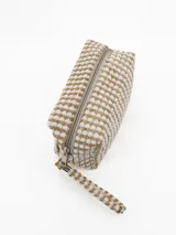 Necessaire de mano con diseño texturizado de puntos en relieve, combinando colores beige y blanco. Cuenta con cierre superior y una correa de muñeca a juego.