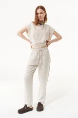 Pantalón babucha color beige de lino y viscosa, con elástico en la cintura y bolsillos laterales.