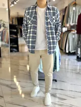 Sobrecamisa de hombre a cuadros en tonos celeste, blanco y azul marino, con forro interno de corderito, bolsillos en el pecho y cierre frontal con botones.