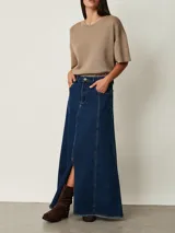 Pollera larga de denim azul con diseño de paneles, bolsillos delanteros y tajo frontal. Presenta terminación deshilachada en el ruedo.