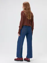 Sweater de punto con diseño de rayas verticales en tonos negro y gris oscuro. Presenta cuello alto tipo polera, mangas largas con puños ajustados y ruedo elástico. Incluye un pequeño bordado en color rojo en el pecho.