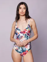 Malla enteriza con escote en V cruzado y breteles finos regulables, confeccionada en tejido estampado con diseño tropical y floral en tonos blancos, fucsias, azules y verdes.