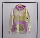 Canguro con capucha y cierre frontal, color beige con estampado de hojas en tonos marrones y amarillos. Mangas largas en color gris.