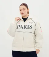 Campera bomber oversized de microfibra color beige, con cierre frontal por cremallera, cuello alto y bolsillos delanteros. Presenta estampado frontal con la inscripción "PARIS 1985" en color negro, además de detalles estampados en las mangas. Cuenta con puños y ruedo elásticos.