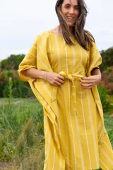 Vestido túnica amarillo con rayas verticales blancas, corte amplio, mangas cortas y lazo para ajustar en la cintura.