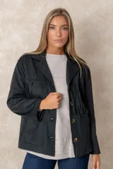 Chaqueta de gamuza sintética color marrón, con diseño de flecos en el pecho y la espalda. Presenta cierre frontal con botones, cuello camisero y bolsillos cuadrados frontales.