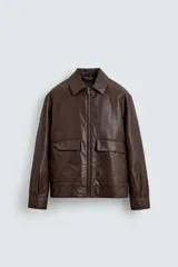 Sobrecamisa de corte relajado confeccionada en tejido efecto piel color marrón. Presenta cuello solapa, cierre frontal con cremallera, mangas largas con puños abotonados y dos bolsillos de plastrón con solapa en la parte frontal.