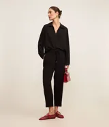 Pantalón de crepé rojo, modelo estilo pijama, de corte fluido, con cintura elástica y lazo de ajuste con terminales metálicas. Cuenta con bolsillos laterales y cierre frontal con cremallera y botón.