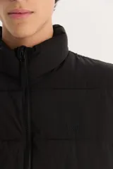 Campera puffer negra con cuello alto y cierre frontal con cremallera.
