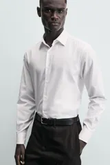Camisa de corte slim fit confeccionada en tejido de algodón. Presenta cuello italiano, manga larga con puños abotonados y cierre frontal mediante botonadura clásica.