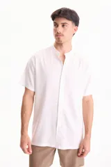 Camisa de lino de manga corta, color blanco, con cuello mao y cierre frontal de botones.