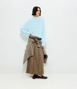 Pollera midi de sastrería con estampado de cuadros, diseño estructurado con pliegues delanteros marcados, cintura ancha con trabillas y cinturón ajustable con hebilla.