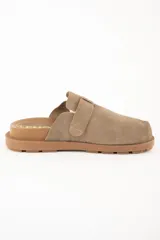 Zueco abierto de cuero gamuzado color visón, con hebilla ajustable y suela marrón con ranuras.