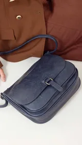 Bandolera morral color bordó, con tapa y broche, bolsillo principal, bolsillos internos organizadores y cierre trasero.