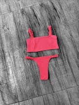 Conjunto de bikini rosa con textura morley. El corpiño es de corte recto con tirantes gruesos y la bombacha es tipo colaless con laterales fruncidos.