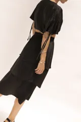 Falda midi negra de seda con cierre invisible lateral, elástico en la cintura y volados.